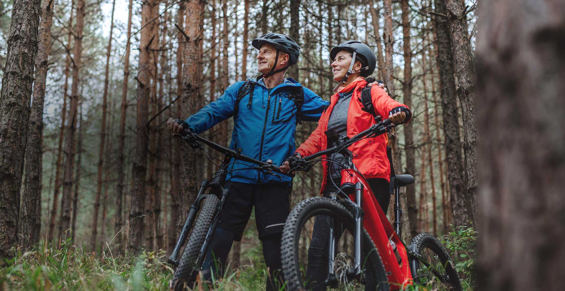 Ein Mann und eine Frau stehen neben ihren E-Bikes im Wald.